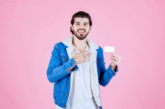 Hombre que sostiene su tarjeta de visita y significa su éxito