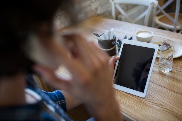 Hombre que sostiene una tableta digital en cafetería