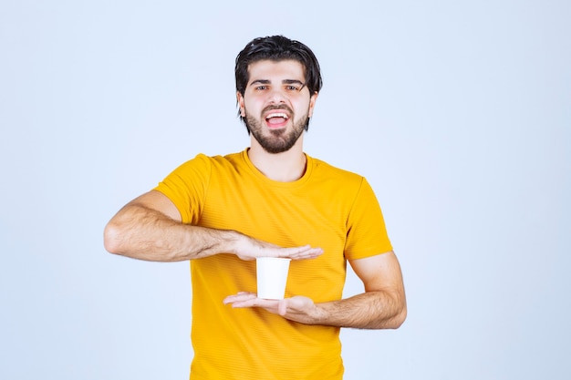 Hombre que sostiene una taza de café desechable entre las manos.