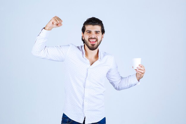 Hombre que sostiene una taza de café y se siente poderoso