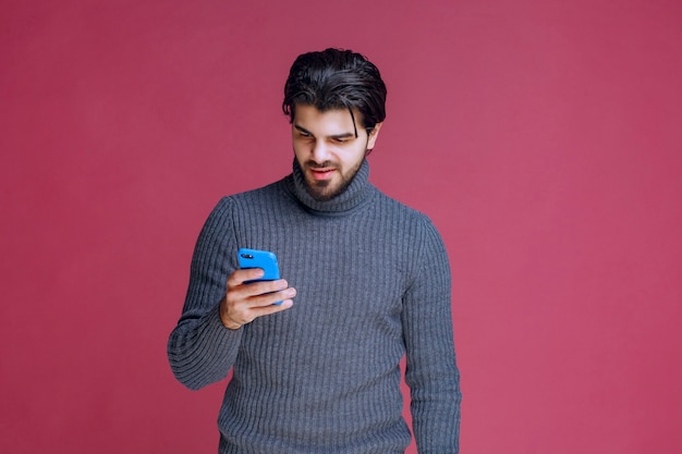 Hombre que sostiene un teléfono inteligente, leyendo mensajes o enviando mensajes de texto.