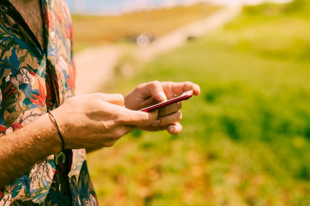 Hombre que sostiene teléfono inteligente en la naturaleza