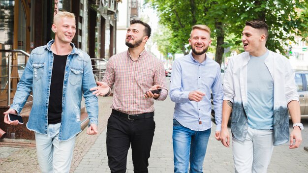 Hombre que sostiene el teléfono móvil en su mano disfrutando con su amigo en la calle