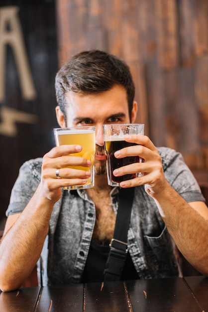 Foto gratuita hombre que sostiene vasos de cerveza y ron en la barra