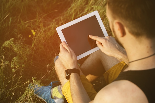 Hombre que trabaja al aire libre con la almohadilla de la tableta. Filtro de instagram vintage retro