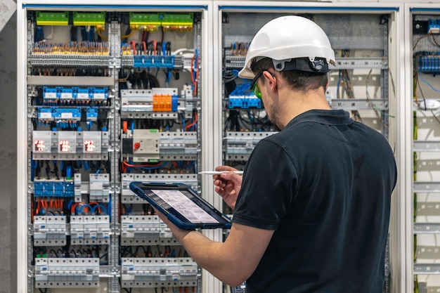 Foto gratuita un hombre que trabaja en una central eléctrica con fusibles usa una tableta
