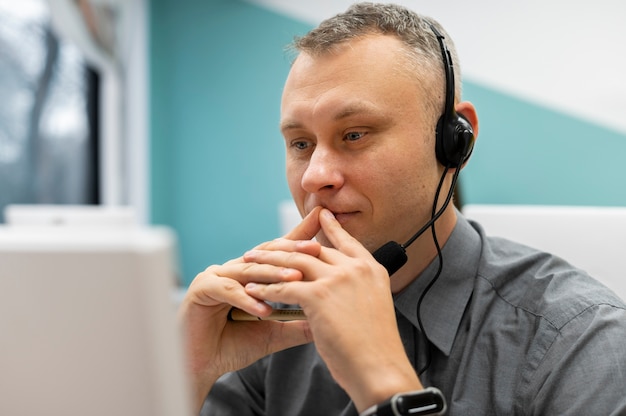 Hombre que trabaja en un centro de llamadas con auriculares y computadora