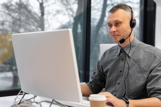 Hombre que trabaja en un centro de llamadas con auriculares y computadora