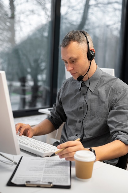 Hombre que trabaja en un centro de llamadas con auriculares y computadora