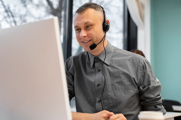 Hombre que trabaja en un centro de llamadas con auriculares y computadora