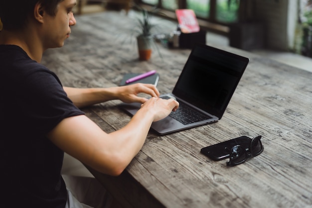 hombre que trabaja con una computadora portátil en un café en una mesa de madera