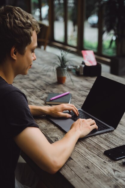 Foto gratuita hombre que trabaja con una computadora portátil en un café en una mesa de madera