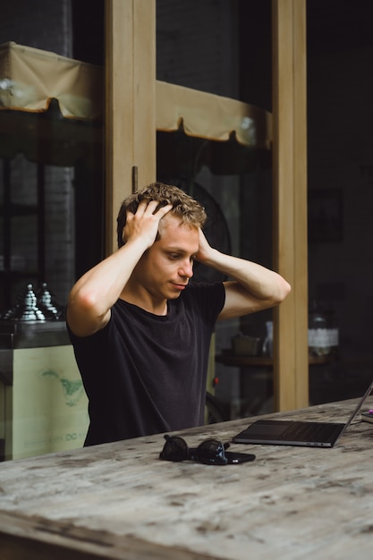 hombre que trabaja con una computadora portátil en un café en una mesa de madera