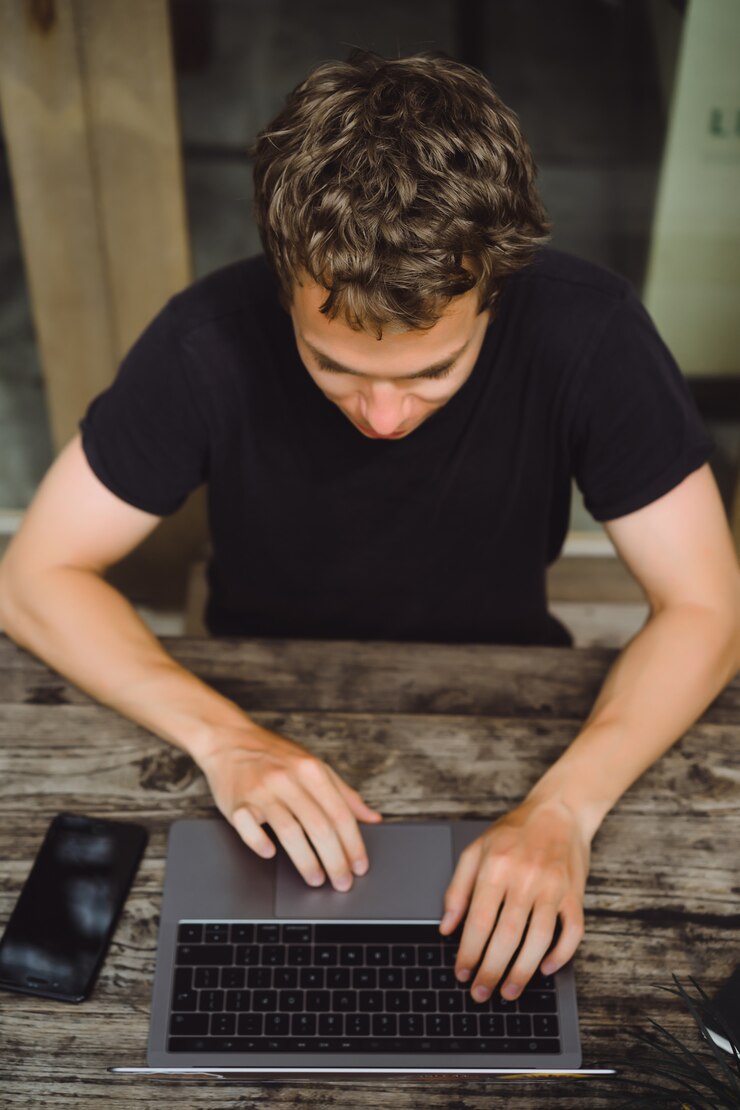 Foto gratuito hombre que trabaja con una computadora portátil en un café en una mesa de madera