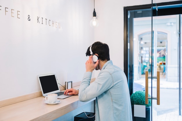 Hombre que trabaja en la computadora portátil en café