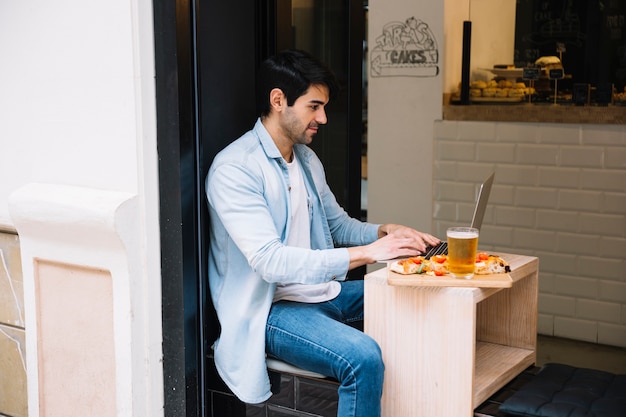 Hombre que trabaja en la computadora portátil en café