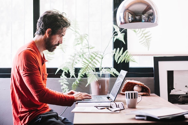 Hombre que trabaja en la computadora portátil en casa