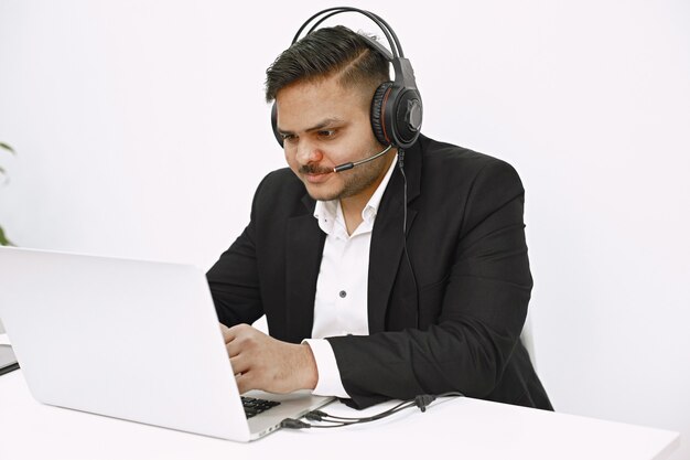 Hombre que trabaja con la computadora portátil. Despachador indio o trabajador de línea directa.