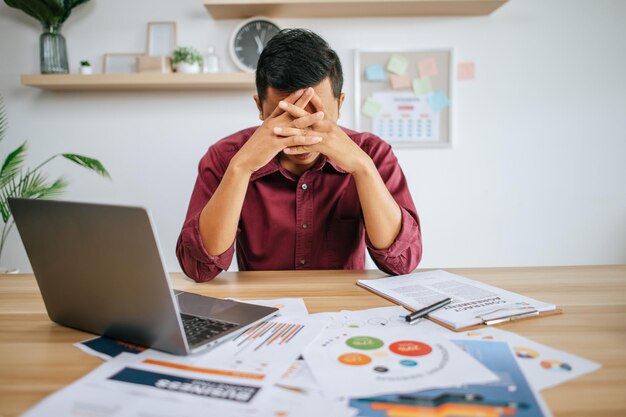 Hombre que trabaja con la computadora portátil y el papeleo con estrés