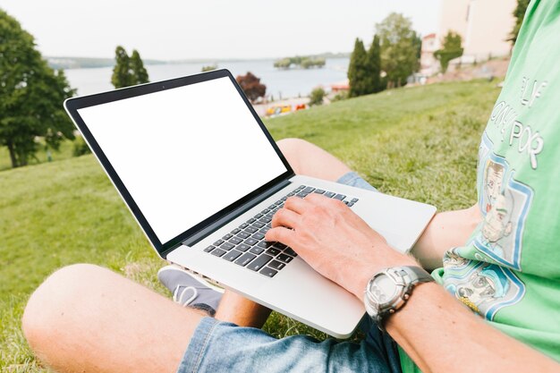 Hombre que trabaja en la computadora portátil en el parque