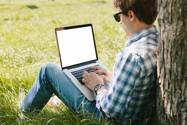 Hombre que trabaja en la computadora portátil en el parque