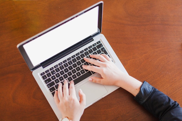 Hombre que trabaja en la computadora portátil que se sienta en la mesa