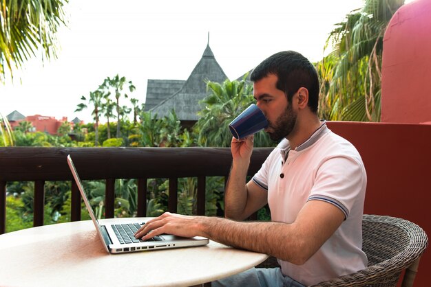 Hombre que trabaja con su computadora portátil en una terraza del hotel