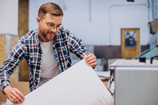 Hombre que trabajaba en la imprenta con papel y pinturas