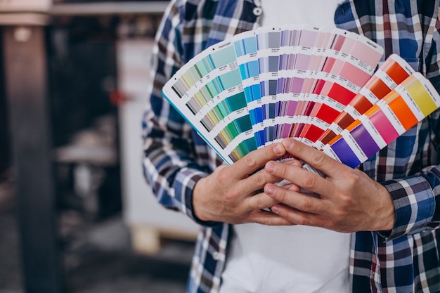 Hombre que trabajaba en la imprenta con papel y pinturas