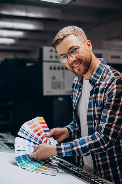 Hombre que trabajaba en la imprenta con papel y pinturas