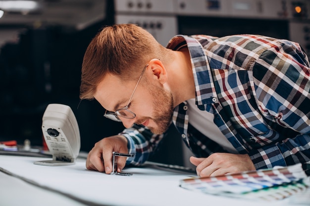 Hombre que trabajaba en la imprenta con papel y pinturas