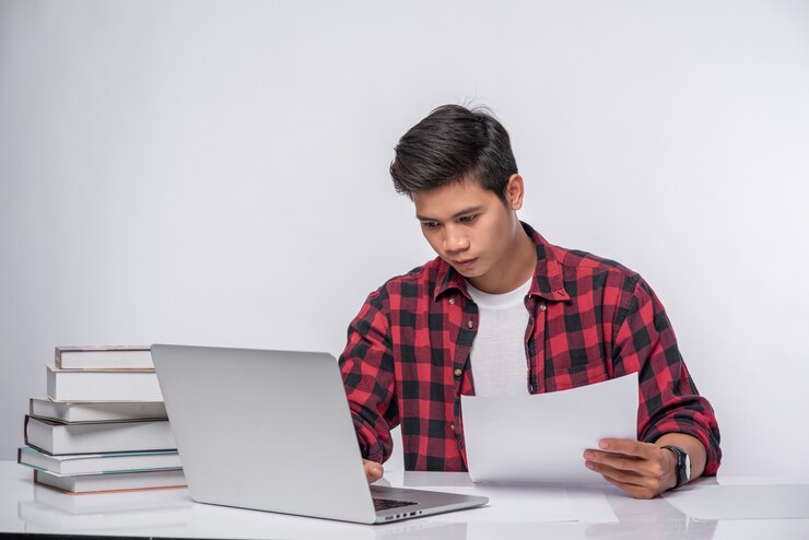 Foto gratuito un hombre que usa una computadora portátil en la oficina y hace un análisis de documentos.