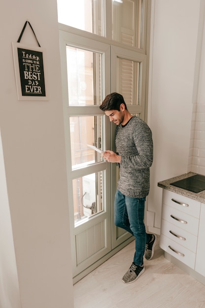 Hombre que usa la tableta cerca de la ventana