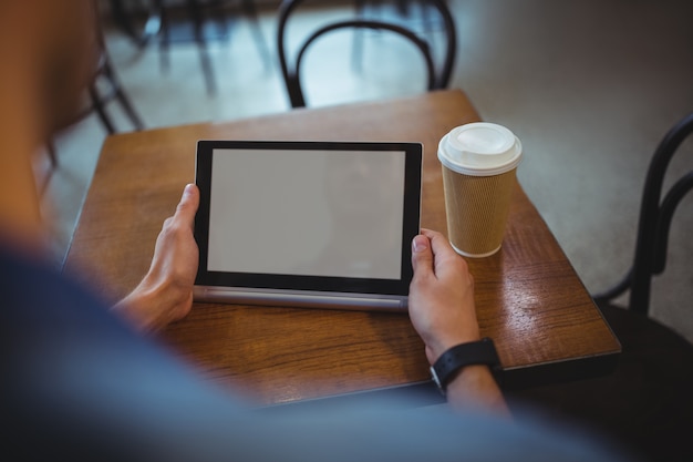 Hombre que usa la tableta digital en el café