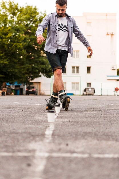 Hombre que usa la taza de disposición mientras que practica rollerskate