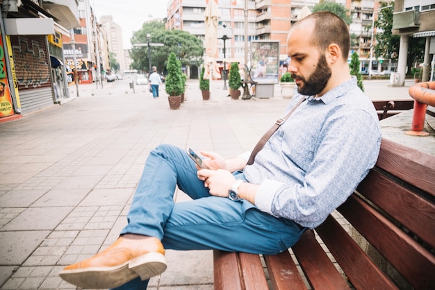 Hombre que usa el teléfono inteligente en el banco