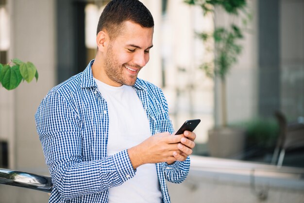 Hombre que usa el teléfono inteligente y sonriendo