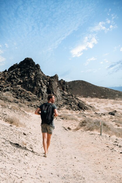 Hombre que viaja en el camino arenoso de la montaña