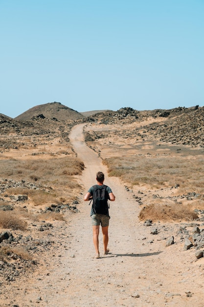 Foto gratuita hombre que viaja en el camino arenoso de la montaña