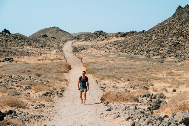 Hombre que viaja en el camino arenoso de la montaña