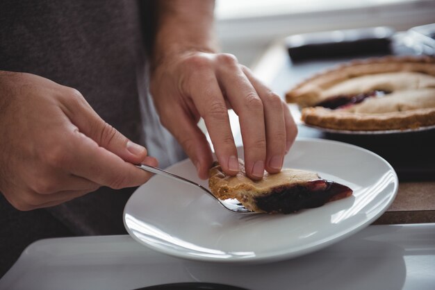 Hombre quitando rodaja de tarta de arándanos