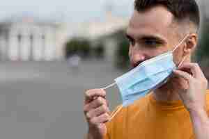 Foto gratuita hombre quitándose la máscara médica al aire libre