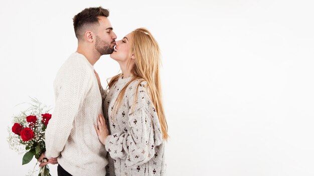 Hombre con ramo besando a mujer