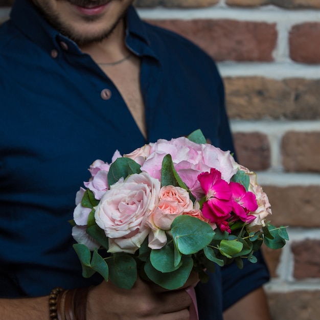 Un hombre con un ramo de rosas blancas y margaritas rosas