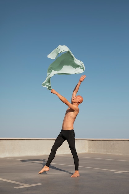 Hombre realizando danza artística en una azotea con cielo azul