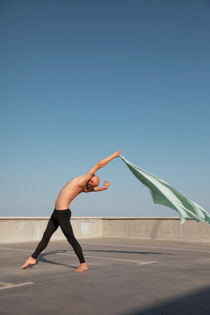 Hombre realizando danza artística en una azotea con cielo azul