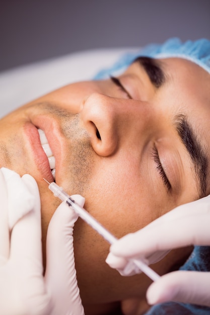 Hombre recibiendo inyección de botox en sus labios