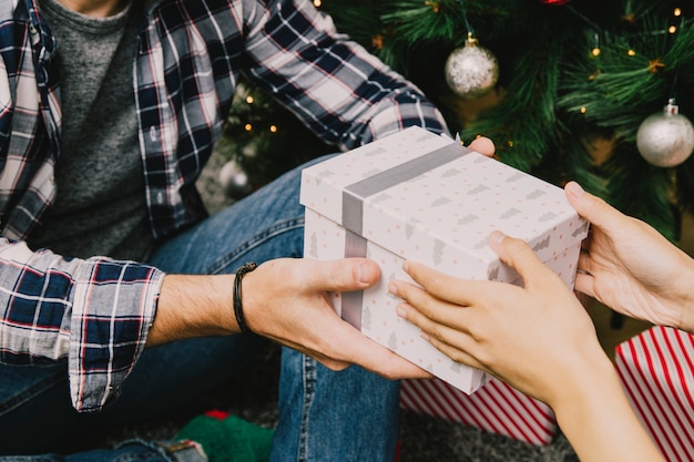 Hombre recibiendo regalo enfrente de árbol de navidad