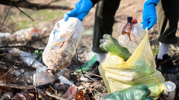 Hombre recogiendo botellas de plástico esparcidas por el suelo