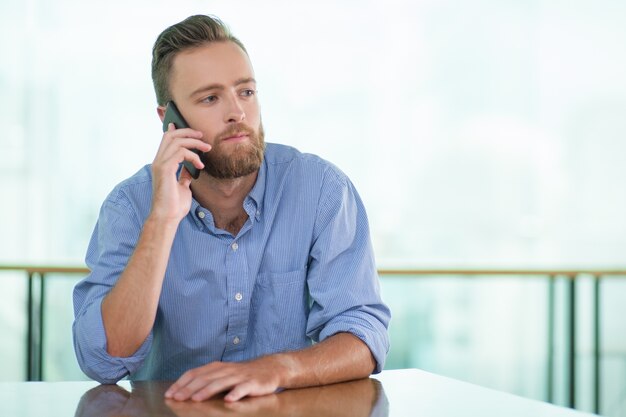 El hombre reflexivo llamando por teléfono en el vector del café